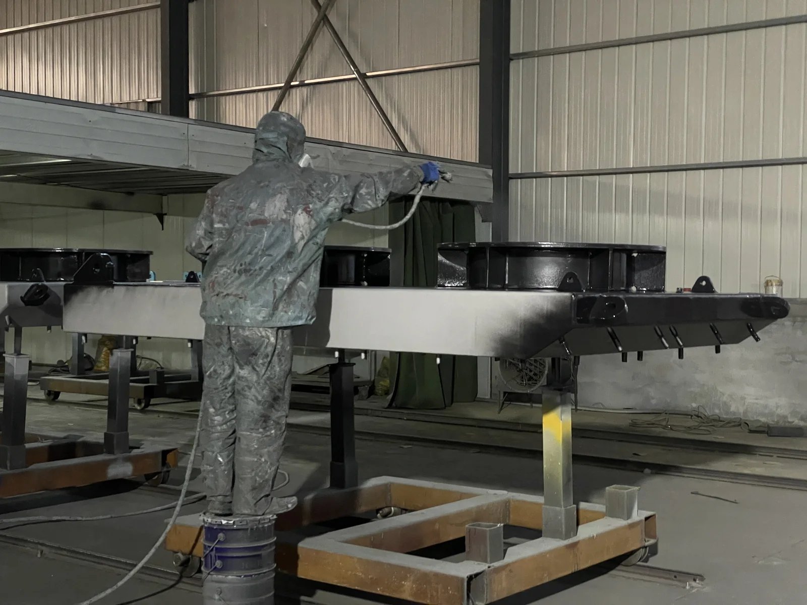Protective coating being sprayed onto a fabricated steel fender panel