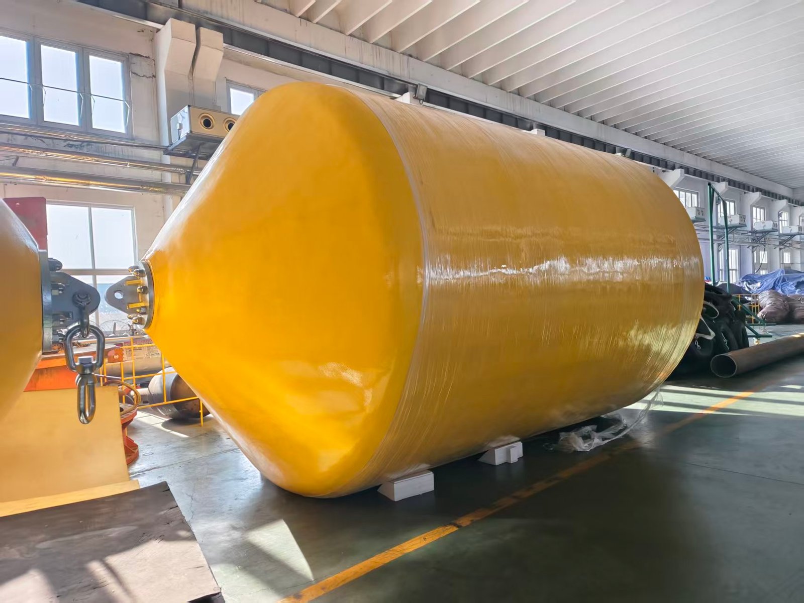 Large yellow foam-filled fender standing in a workshop.