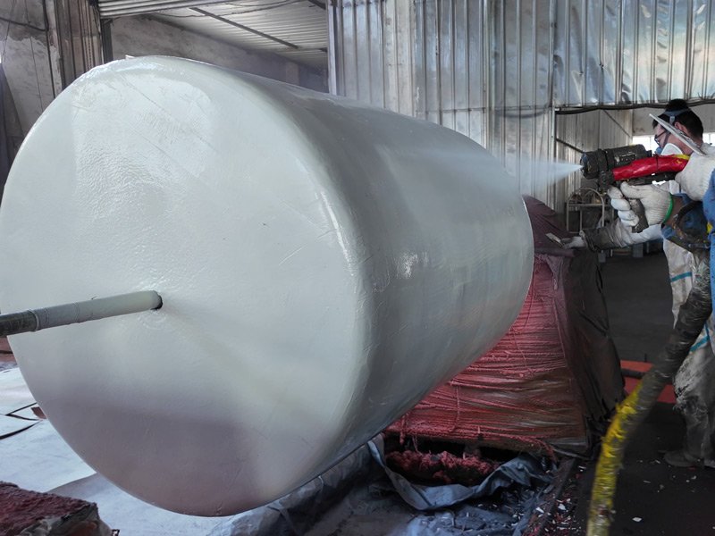 Worker applying a polyurethane outer coating to a large foam-filled fender.