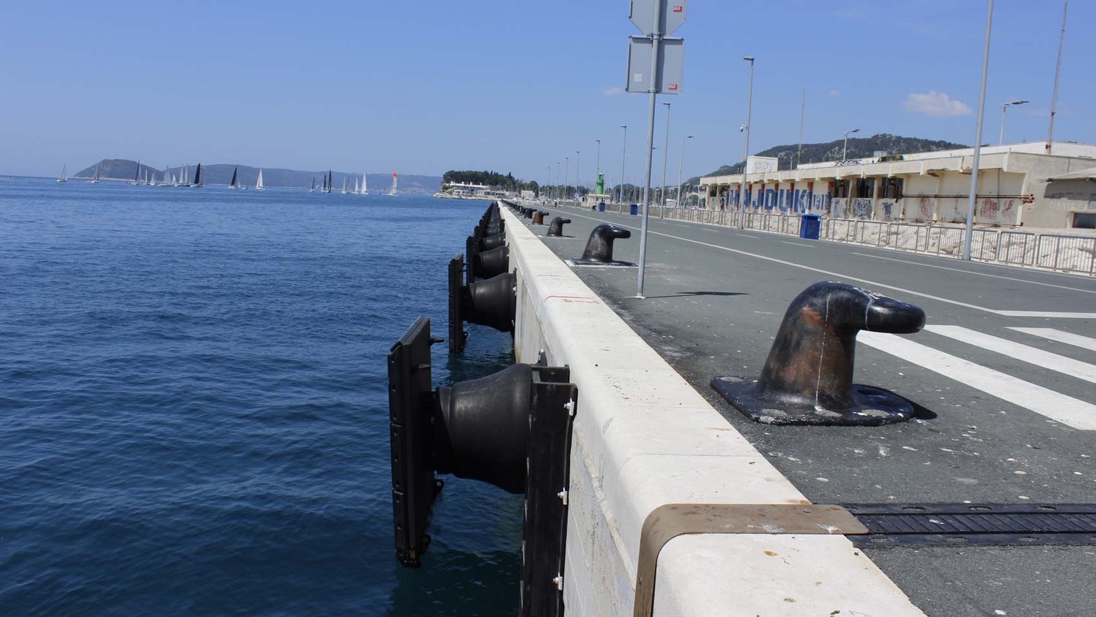 Molded rubber fender panels and chains installed along a quay wall