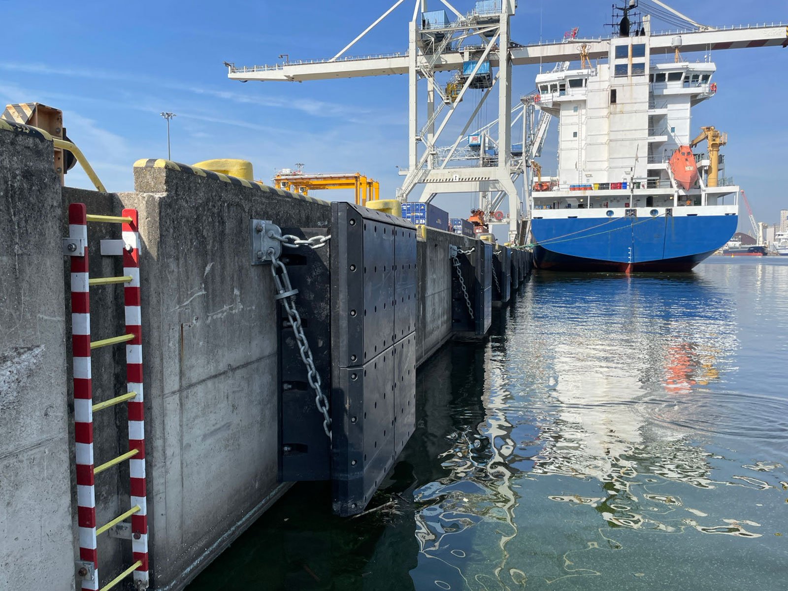 Molded rubber fender panels with chains installed along a container berth beside a vessel