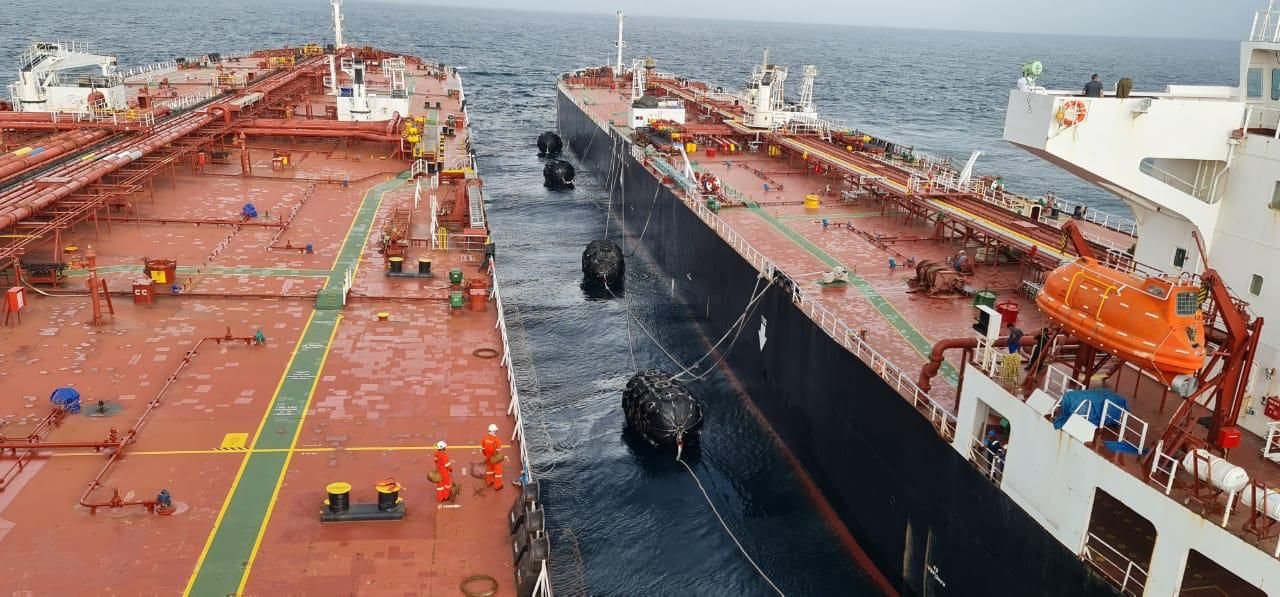 Multiple black pneumatic fenders suspended between two tanker hulls during a ship-to-ship transfer