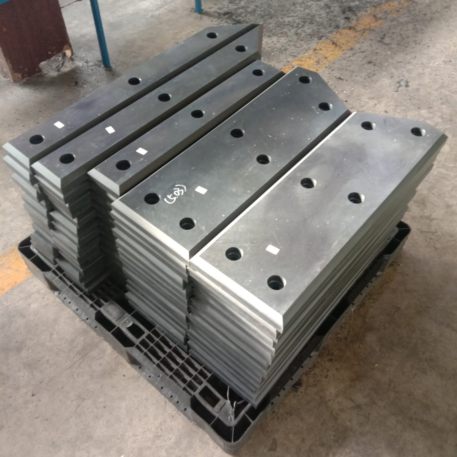 Multiple black machined UHMW-PE pads in different rectangular sizes, with fixing holes.